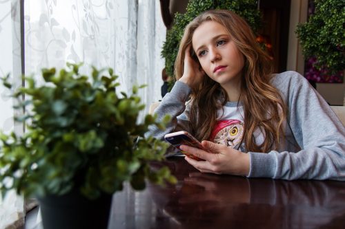 A sad teen thinking about depression, whether she would join a virtual therapy with a doctor or not. Check this out.